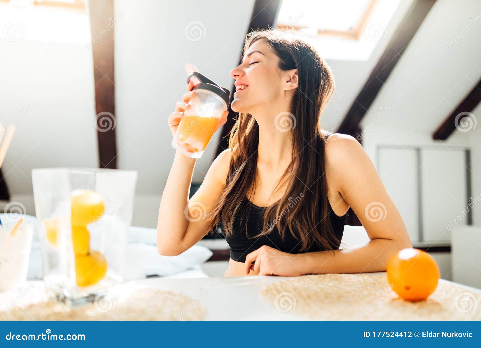 woman at home drinking orange flavored amino acid vitamin powder.keto supplement.after exercise liquid meal.weight loss