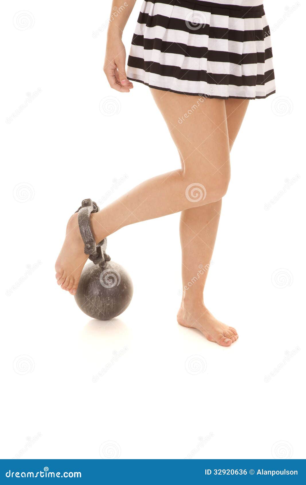 woman in prison outfit skirt with ball and chain on foot Stock Photo