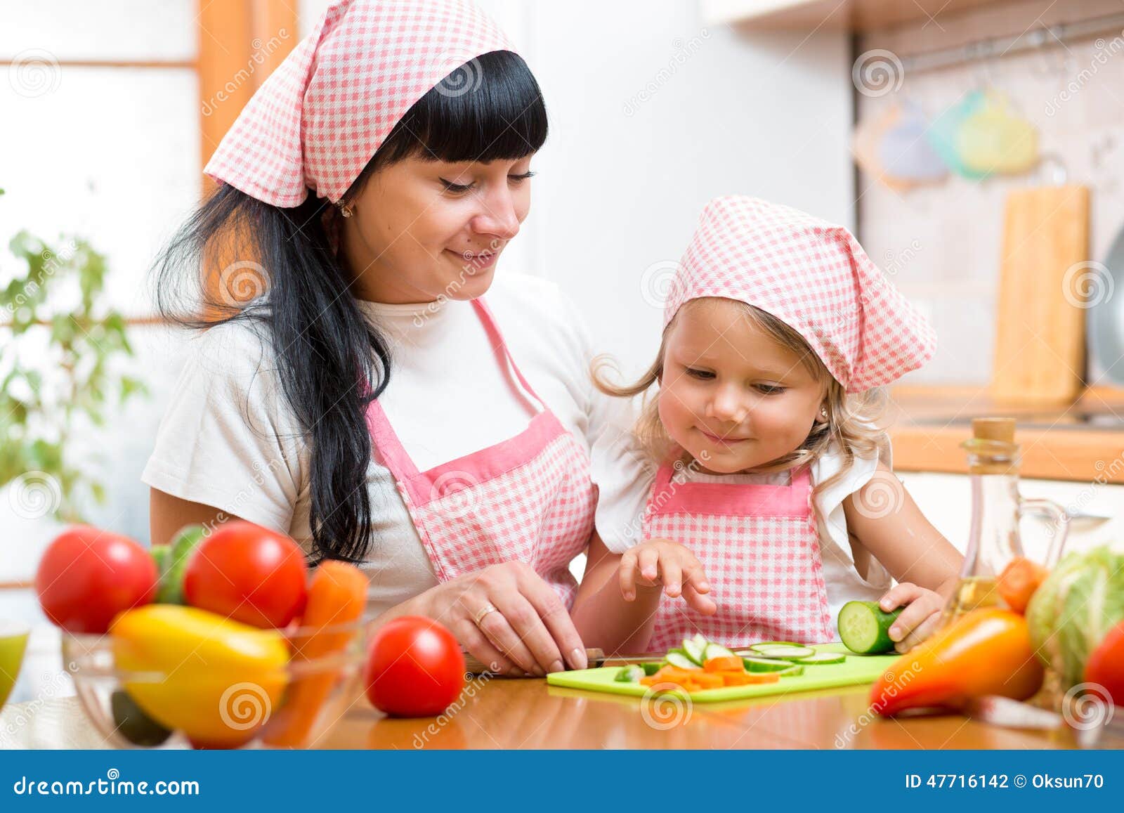 Woman and Kid Daughter Preparing Vegetables at Kitchen Stock Photo