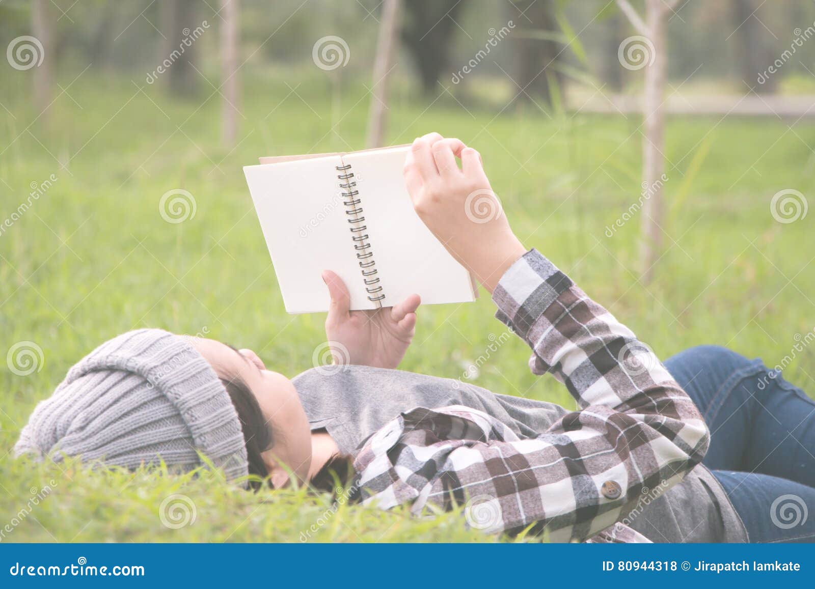 woman laying and lookin book in a park