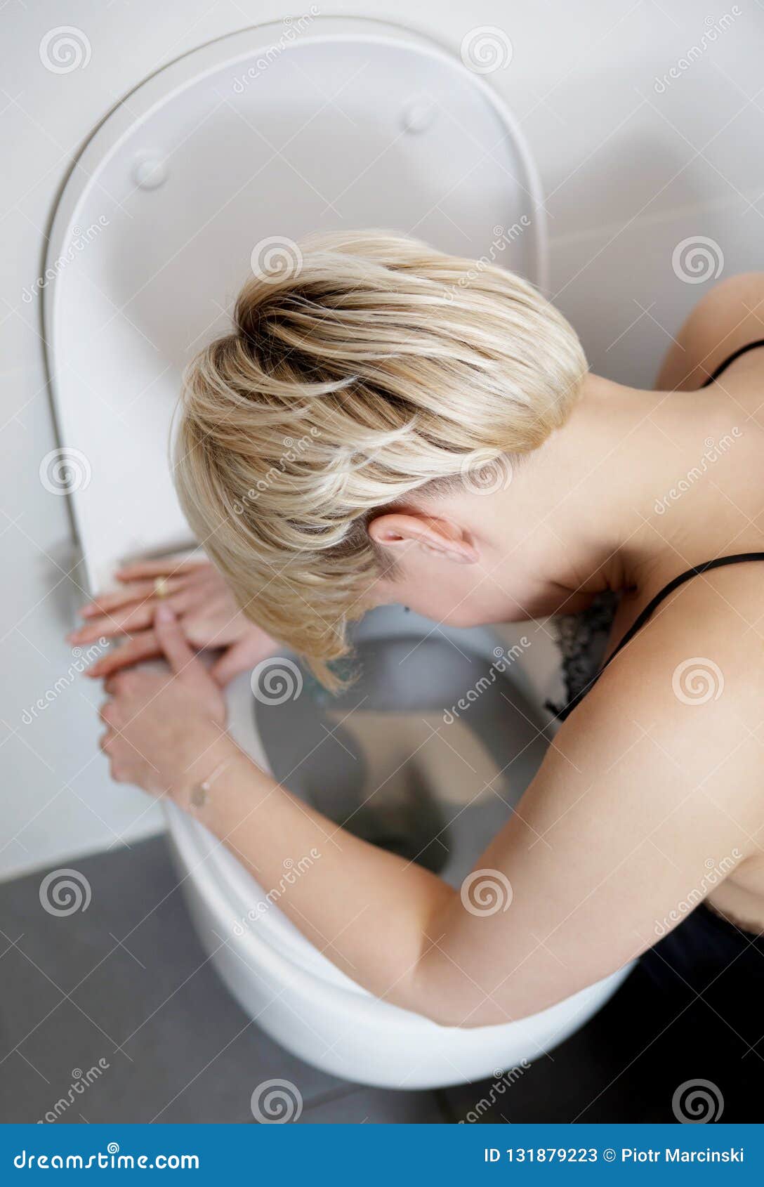 Woman leaning on open toilet seat at indoor bathroom 