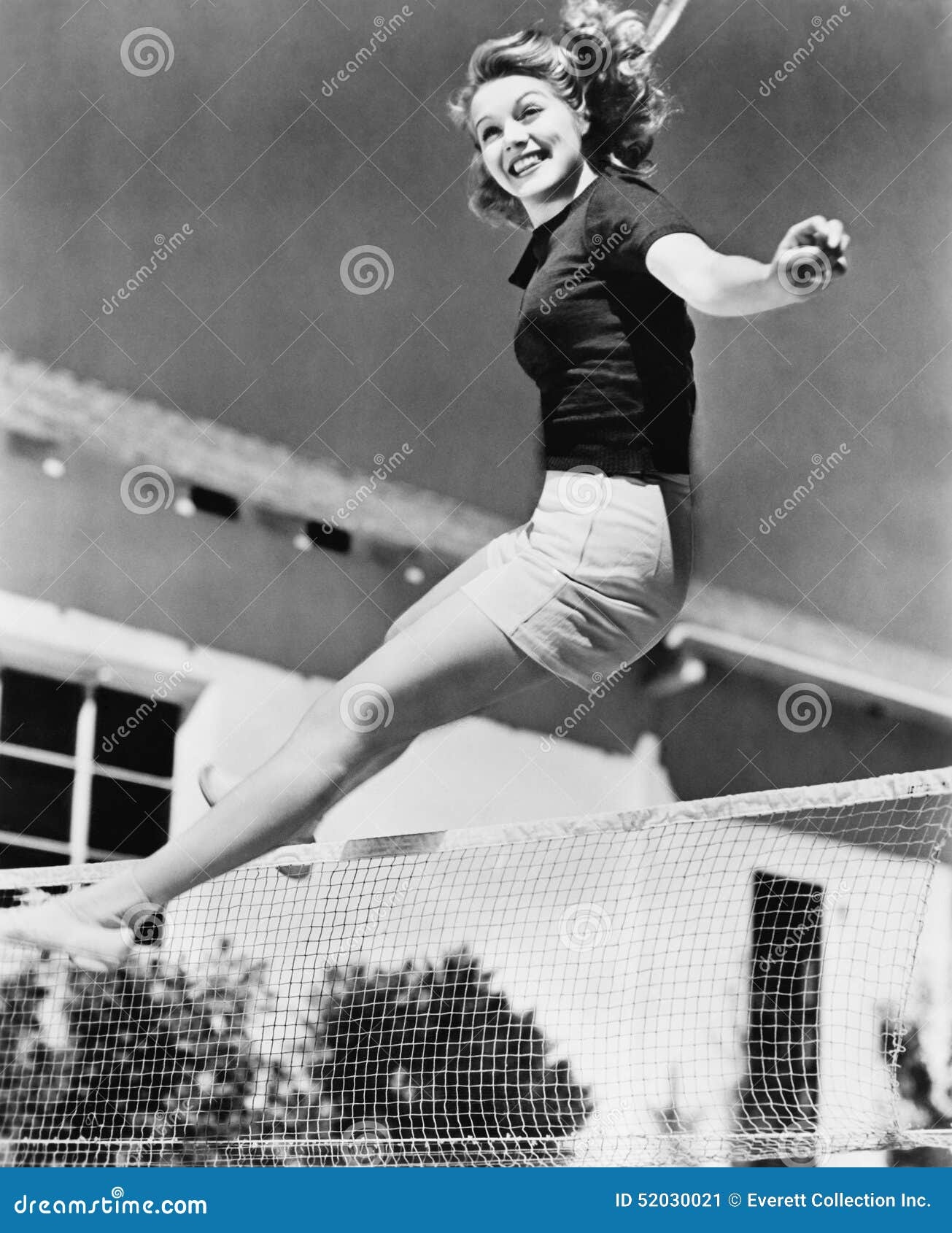 woman leaping over a tennis net