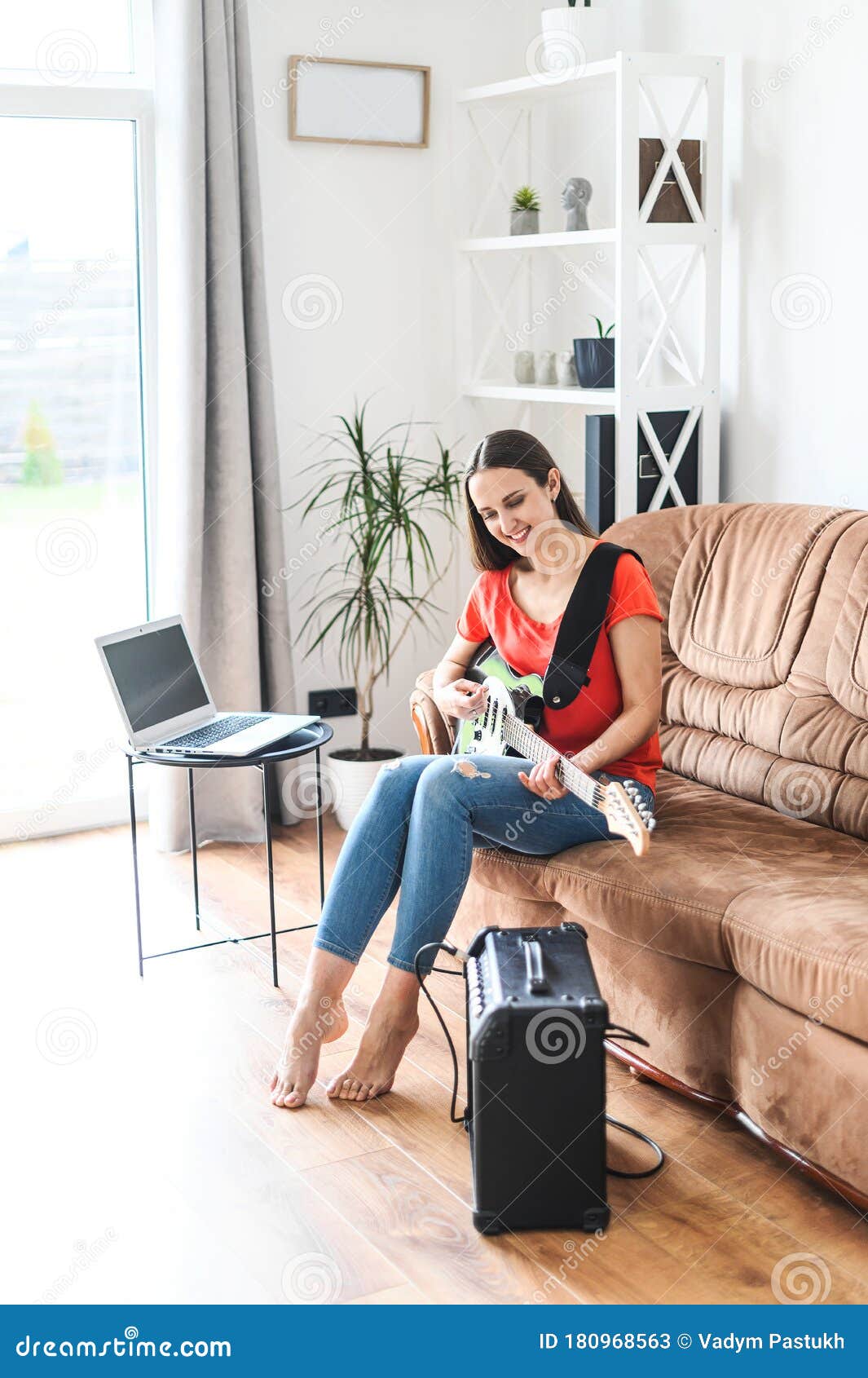 a woman learns to play electric guitar at home