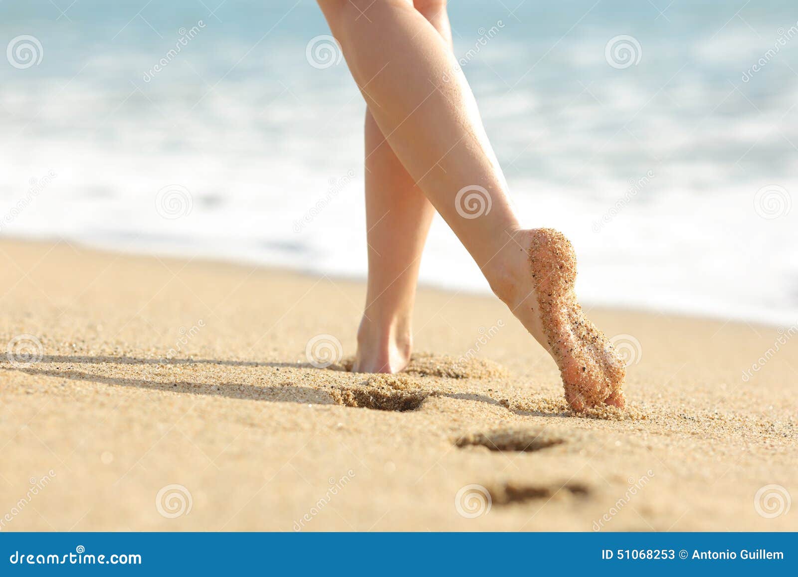 woman legs and feet walking on the sand of the beach
