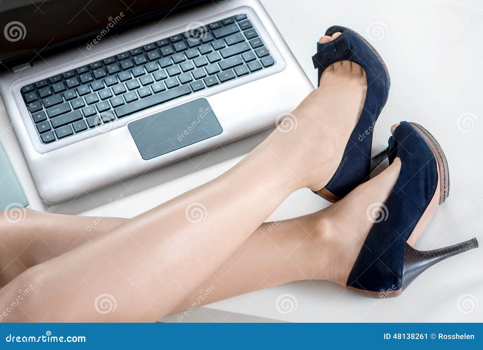 Woman legs and laptop. Woman legs with heels on the office table