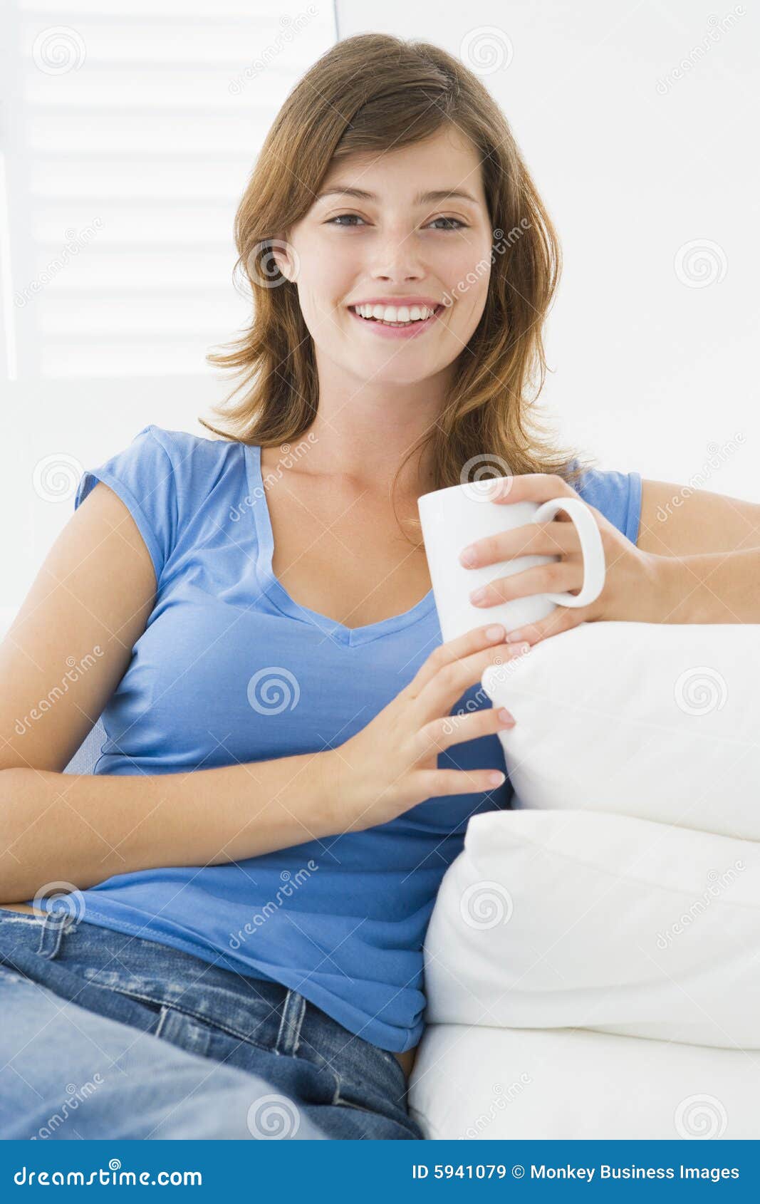 Woman in living room with coffee smiling at camera