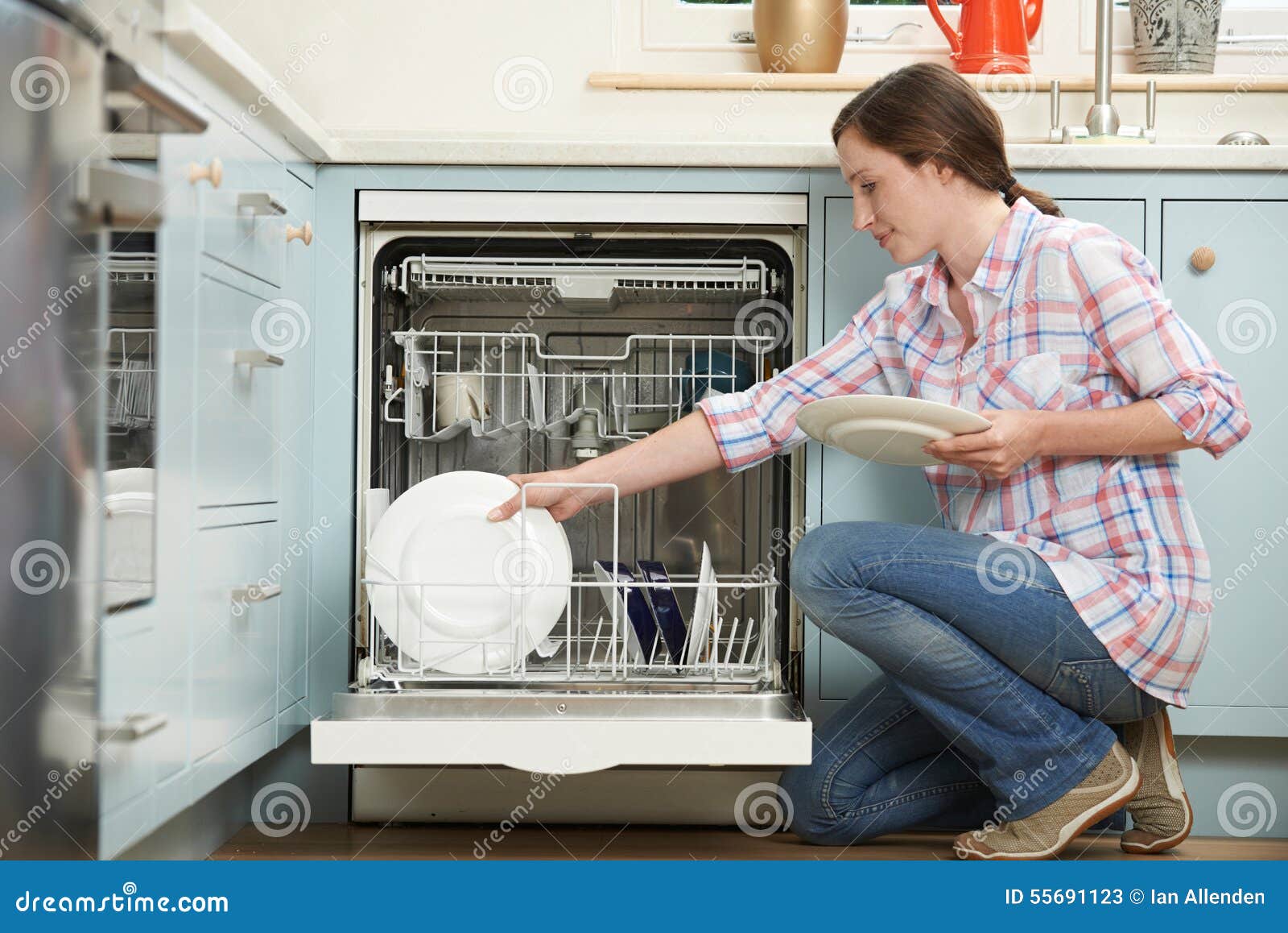 woman loading dishwasher in kitchen