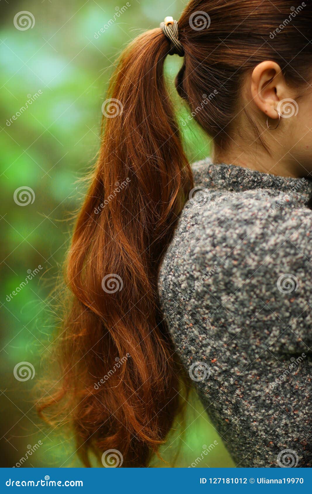 woman with long thick brown hair pony tale close up photo on green summer garden background