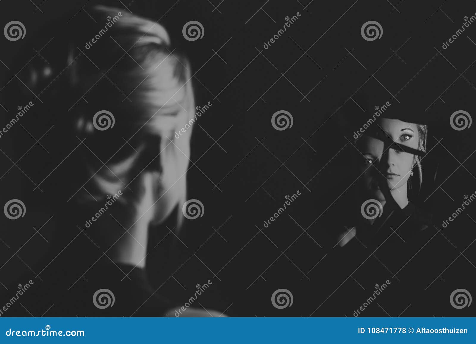 woman looking at her face in shards of broken mirror artistic co