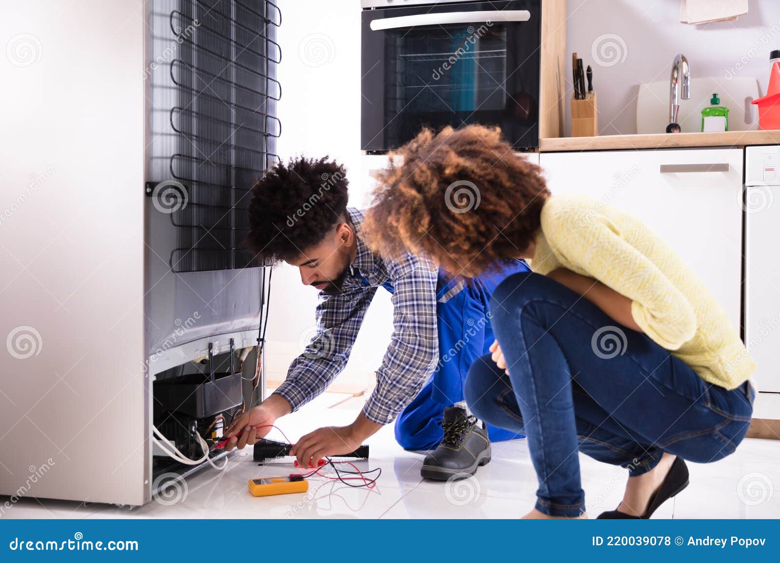 technician examining refrigerator with digital multimeter