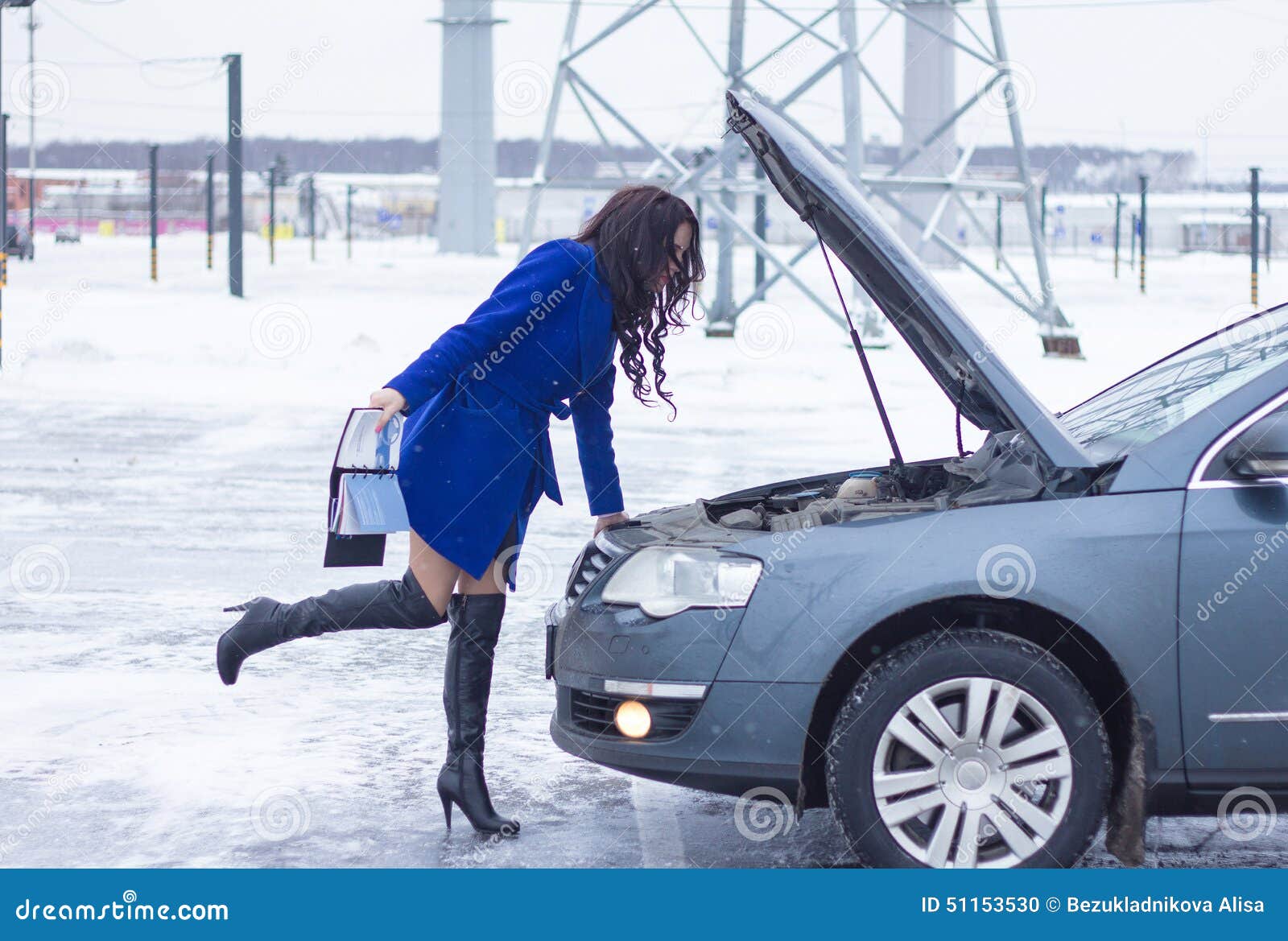 Woman Looks at the Engine of Her Car and Holding a Manual Car Stock
