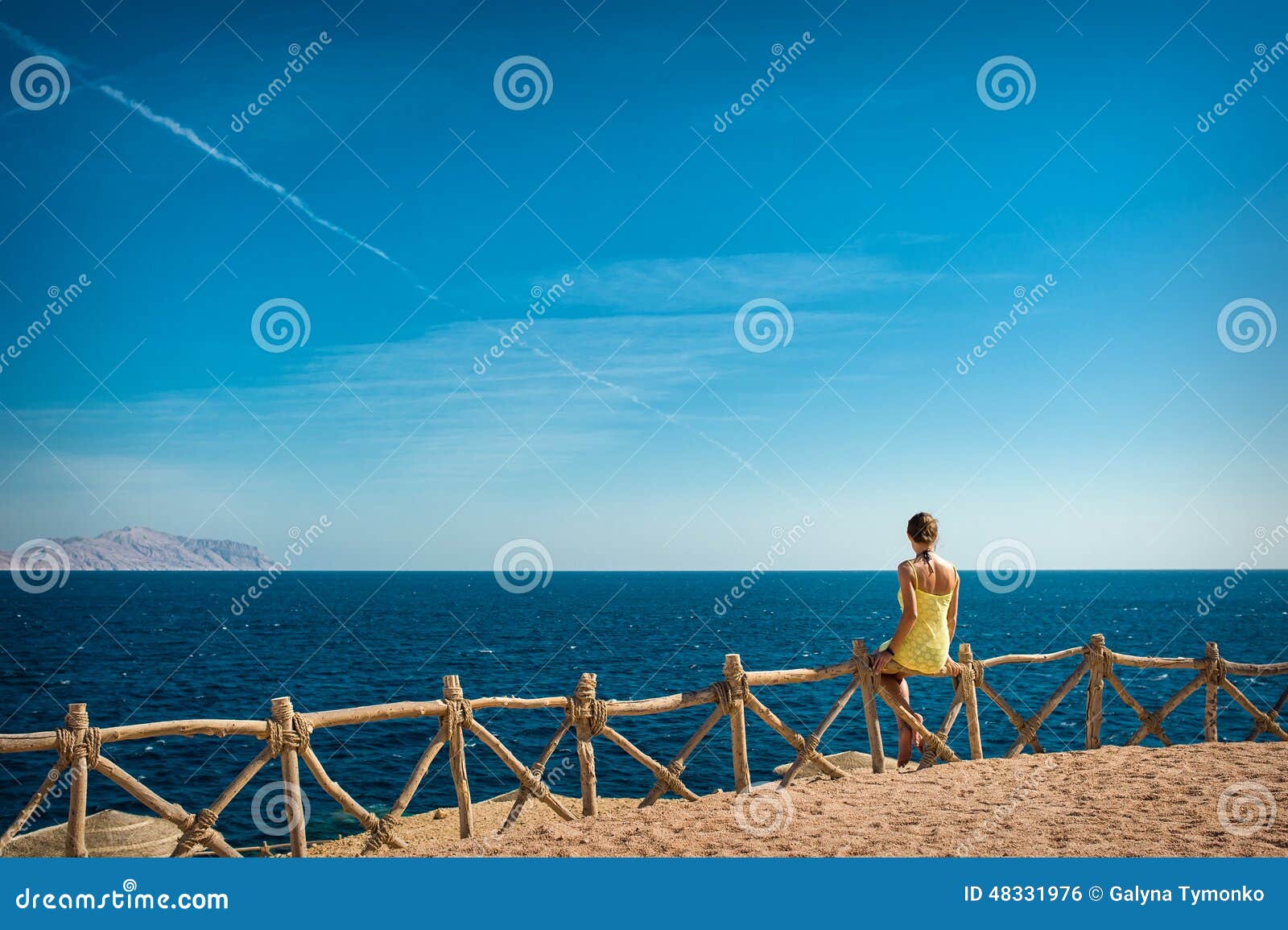 woman looks at the sea and the island of tiran