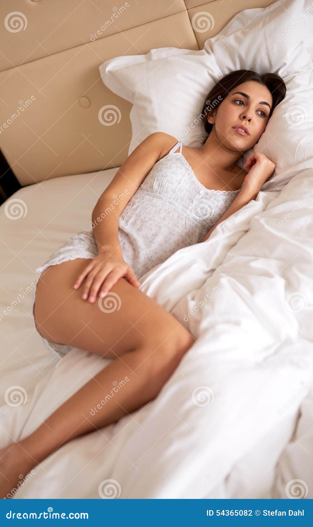 Woman Lying in Bed with Hand on Thigh. Stock Photo Image of plush