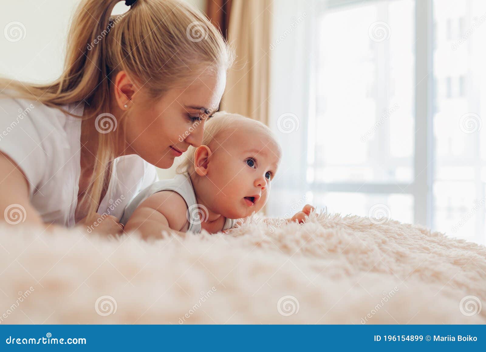 Woman Lying on Bed with Her Baby. Mother Hugging Kid Stock Image ...