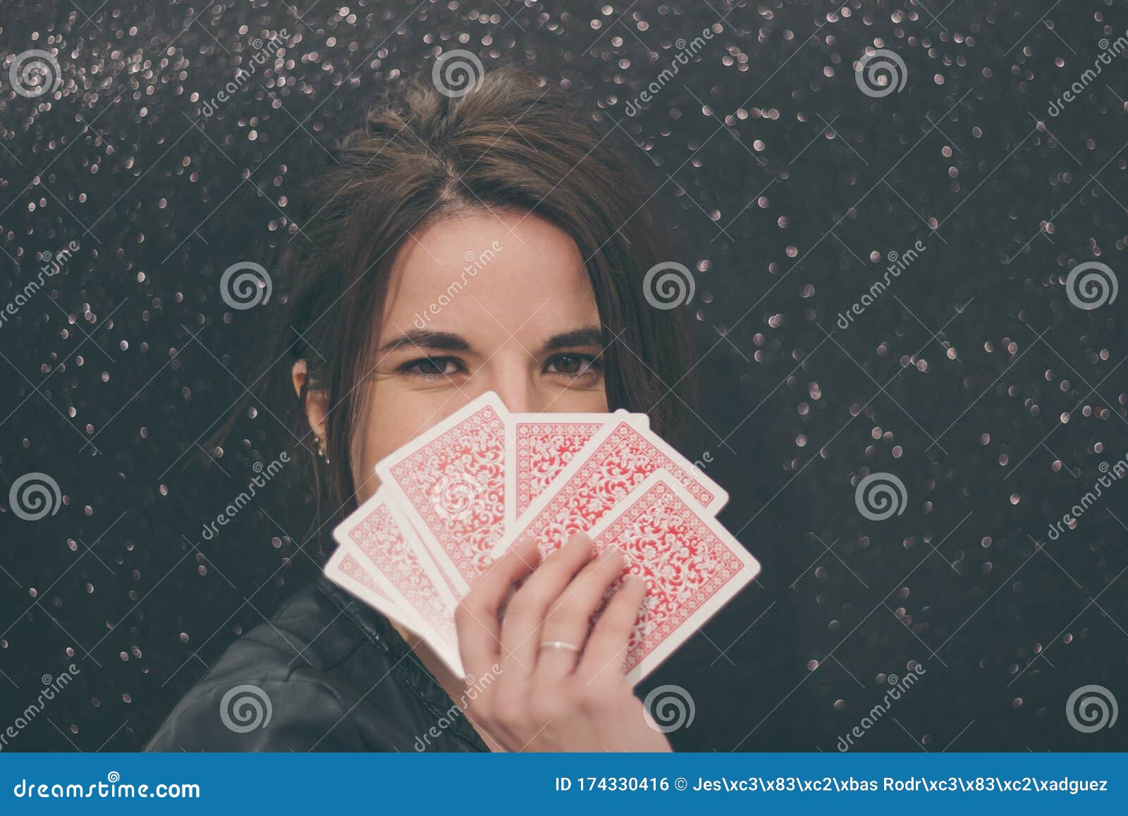 Woman Magician Covering Her Face with Playing Cards on Bright Black ...