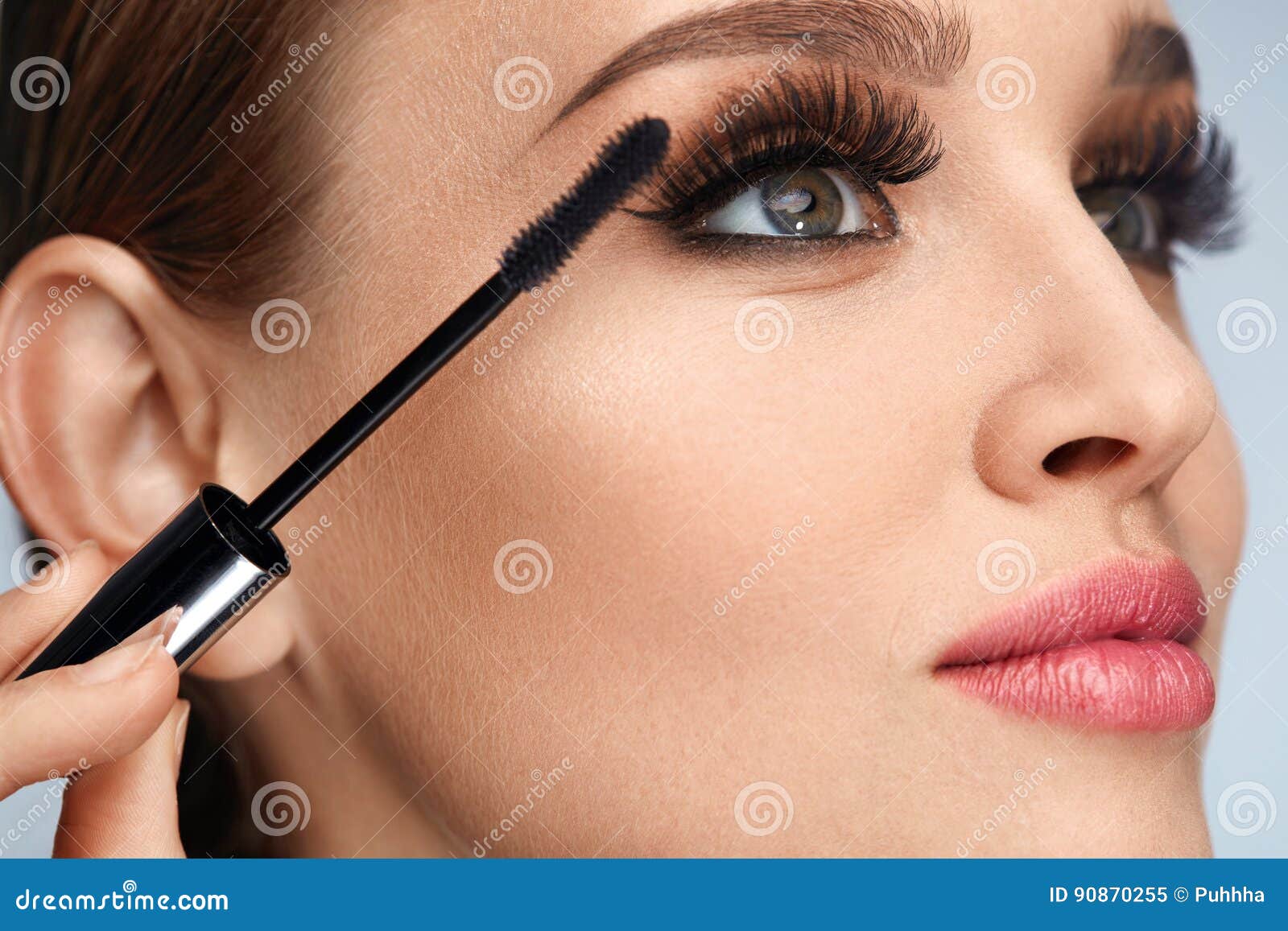 woman with makeup, long eyelashes applying mascara. doing makeup