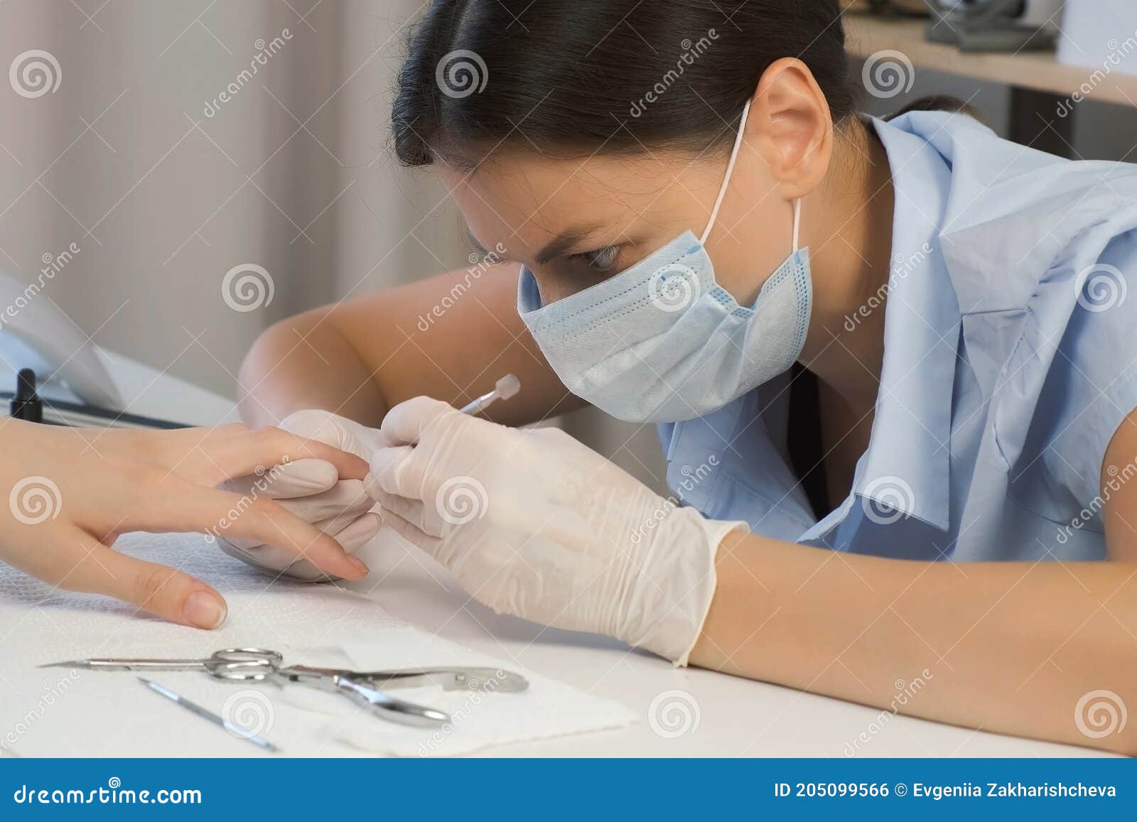 woman manicurist master is removing cuticle and pterygium using pusher.