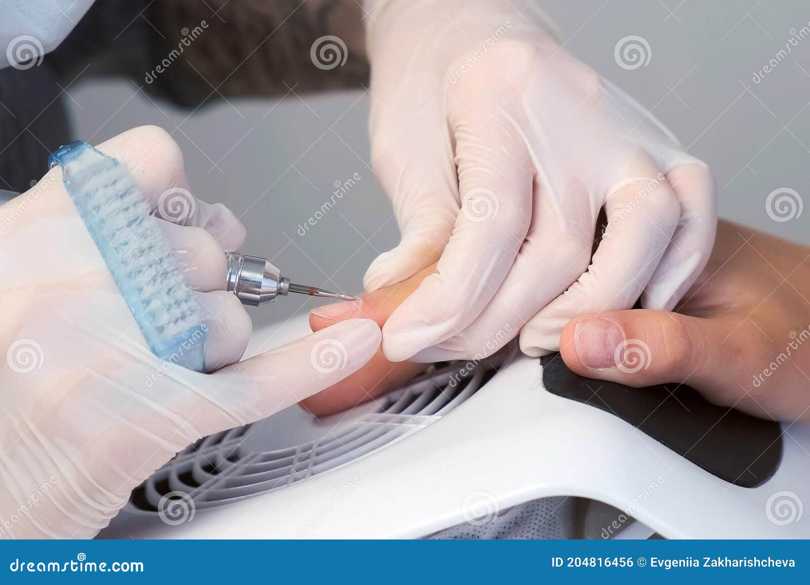 woman manicurist removing cuticle and pterygium using apparatus, closeup view.