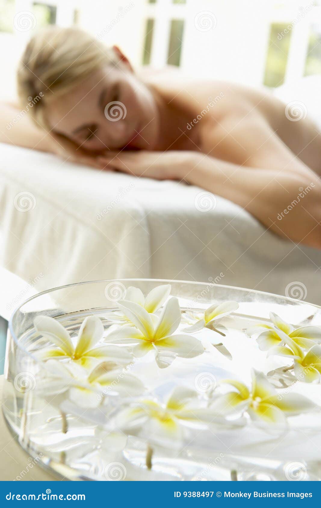 woman on massage table with flowers in foreground