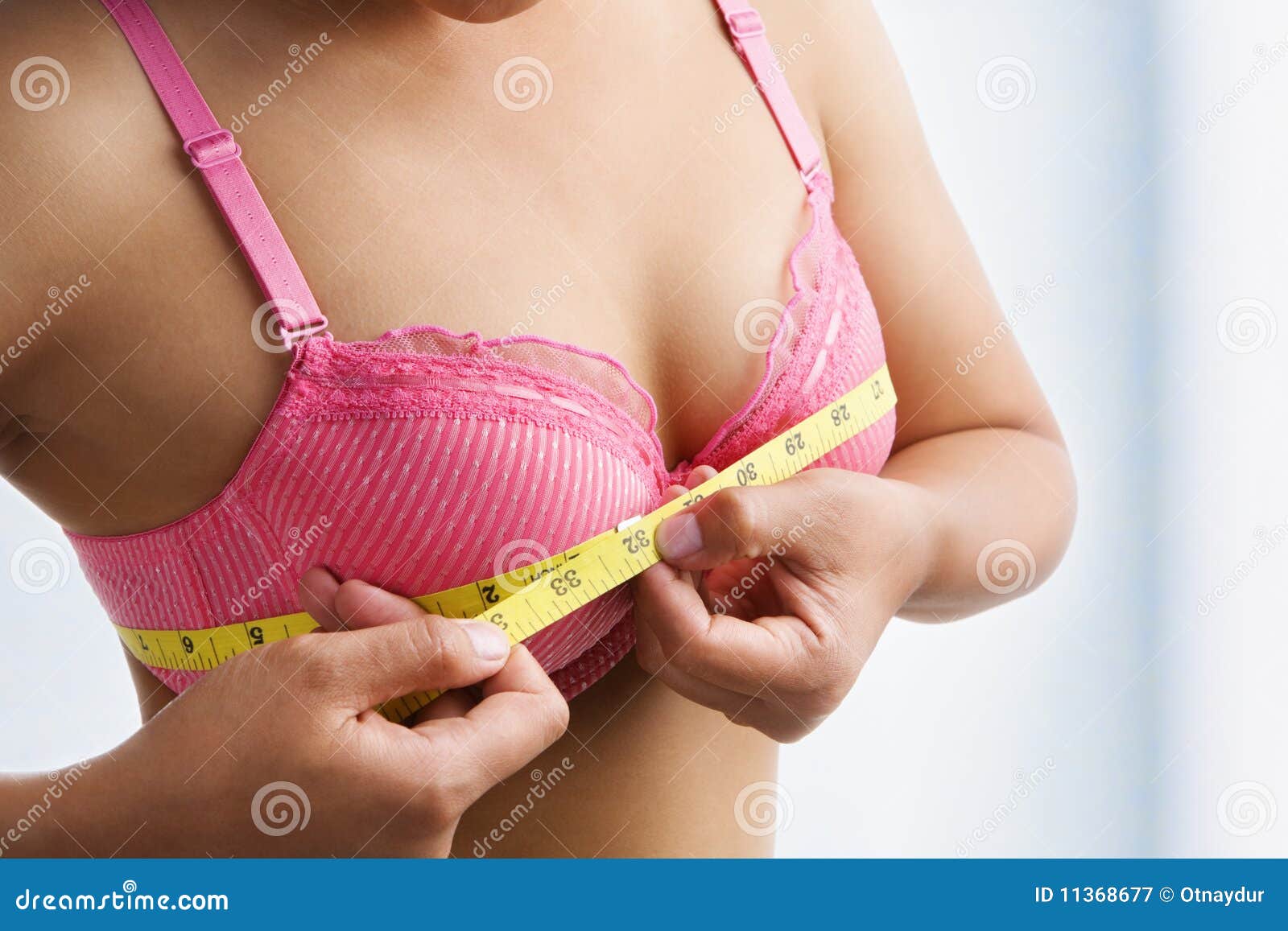 Girl wearing pink bra to examine their breasts. Stock Photo by