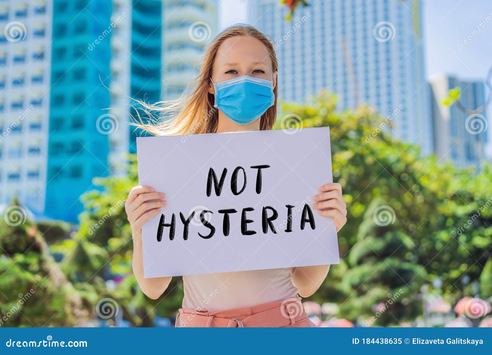 woman in medical mask prevents coronavirus disease holds a poster not histeria hand written text - lettering  on