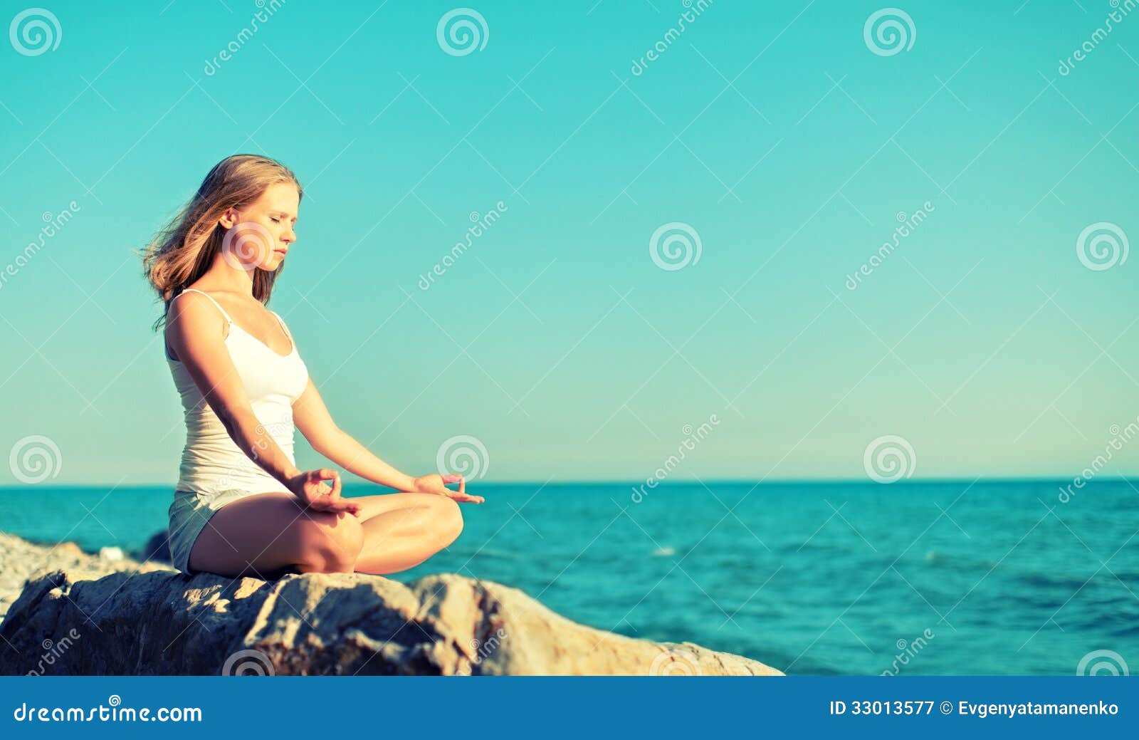 woman meditating in lotus yoga on beach