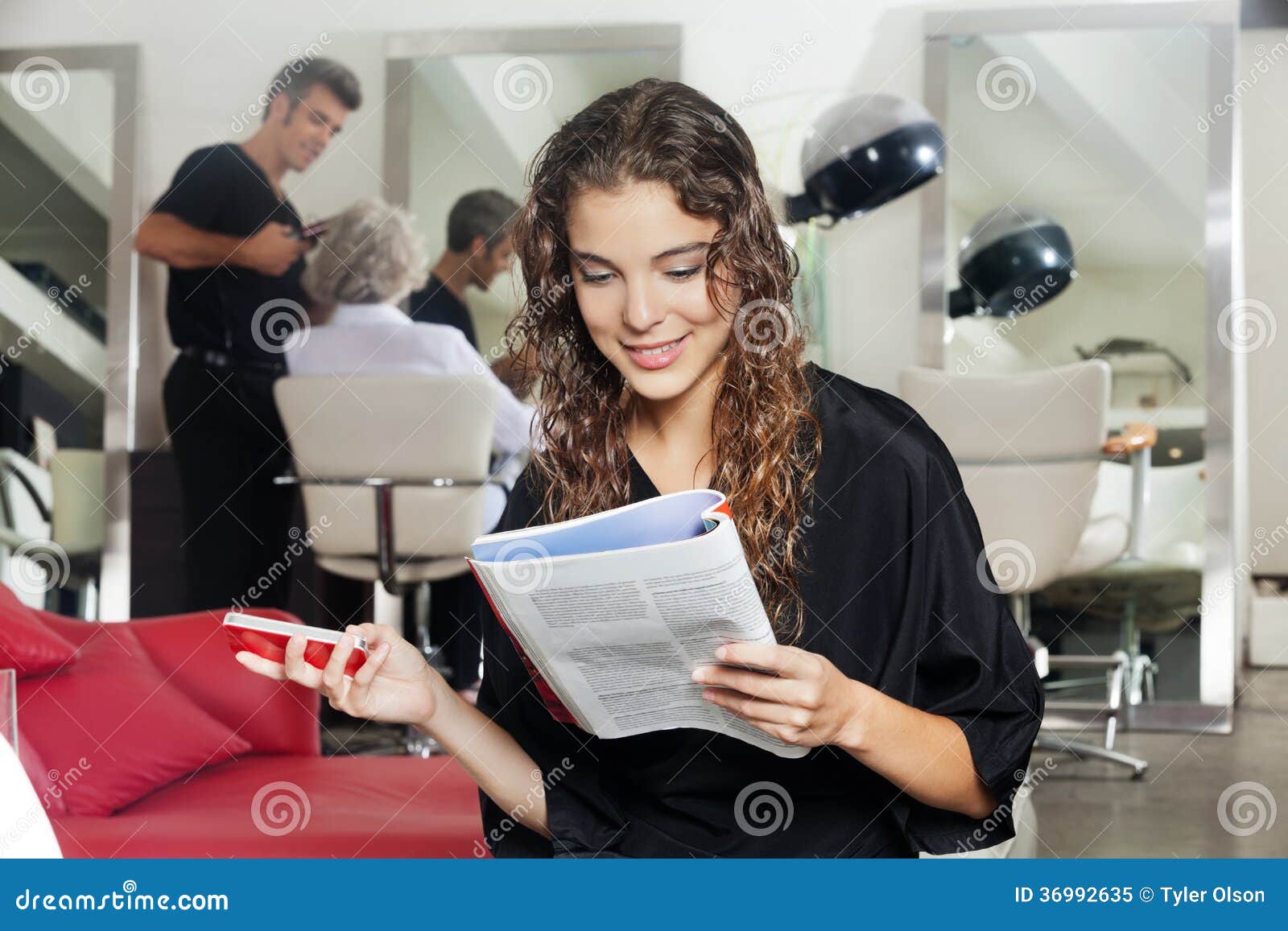 Woman With Mobile Phone Reading Magazine At Hair Stock Image