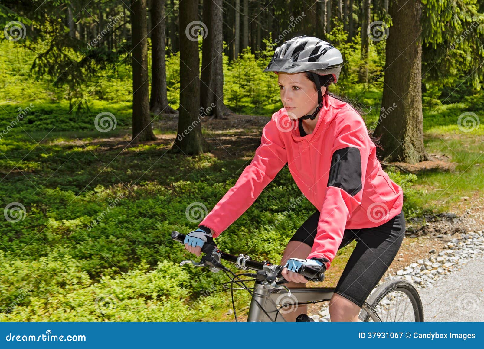 woman mountain biking in forest sunny day