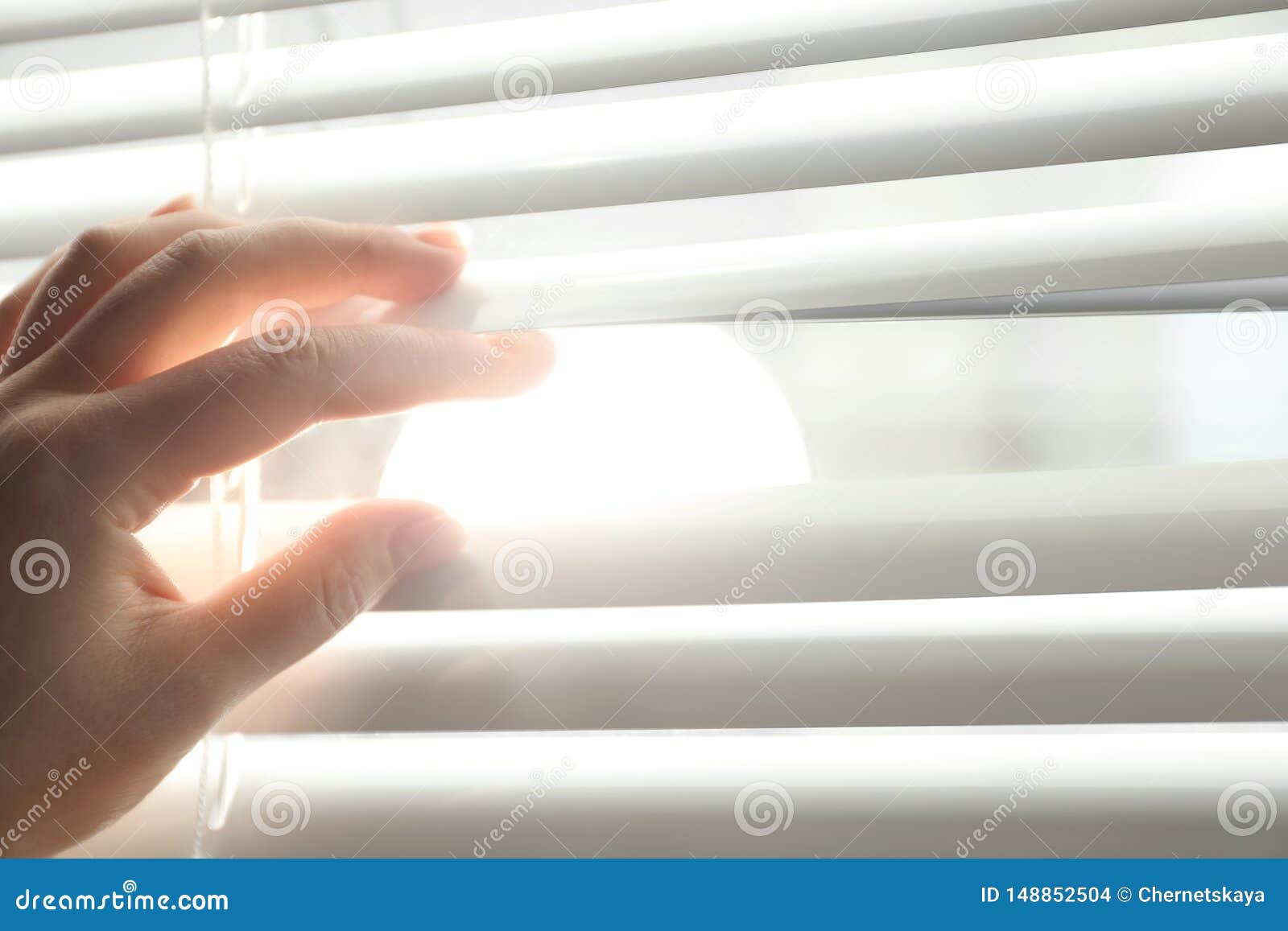 Woman Opening Horizontal Window Blinds at Home. Space for Text Stock