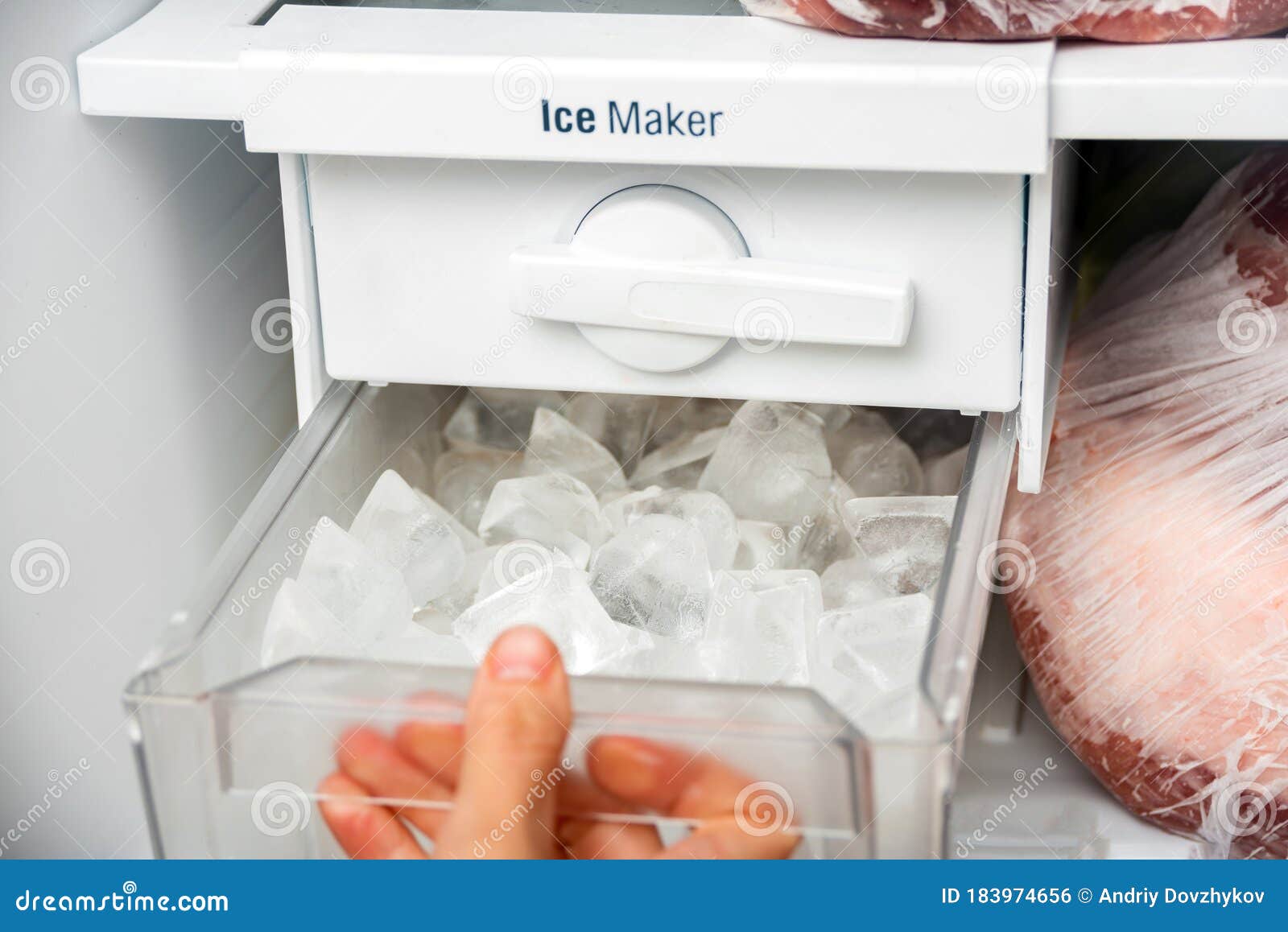 a woman opens an ice maker tray in the freezer to take ice cubes to cool drinks