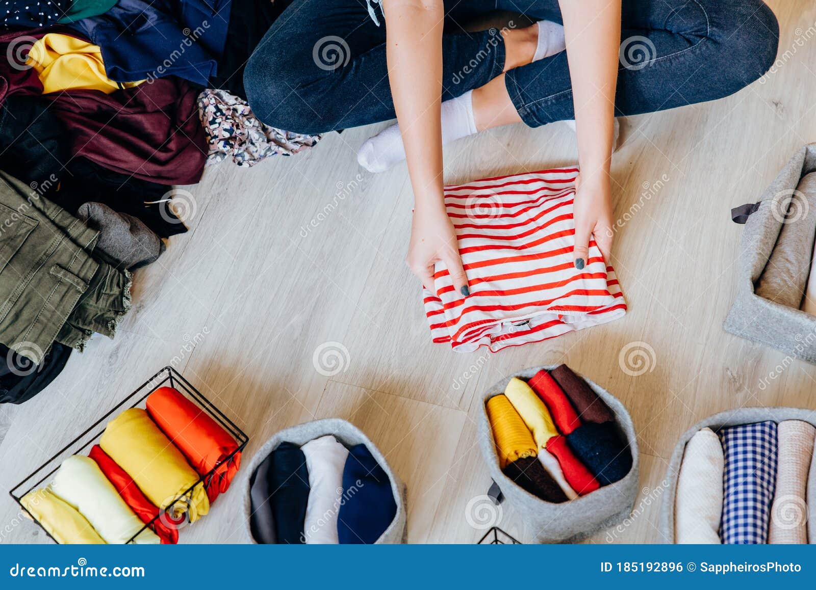 woman folding pile of clothes on the floor, organizing stuff