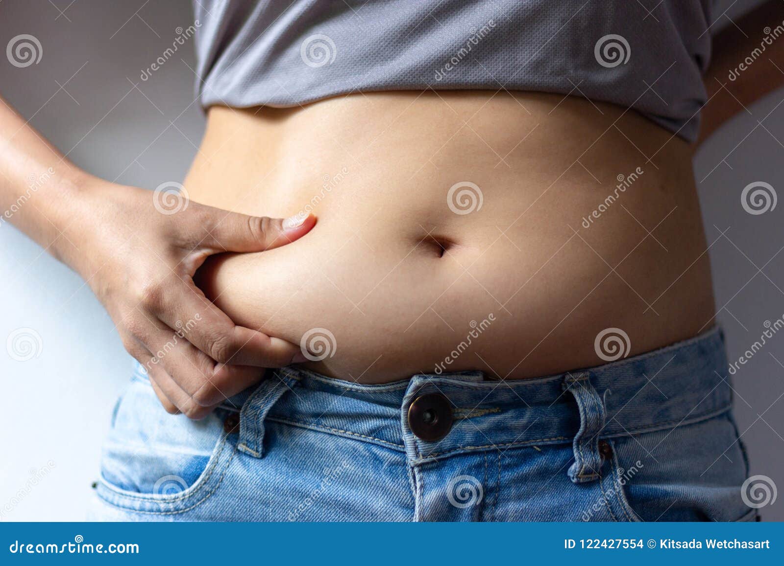 woman with overweight abdomen. hand holding excessive fat belly