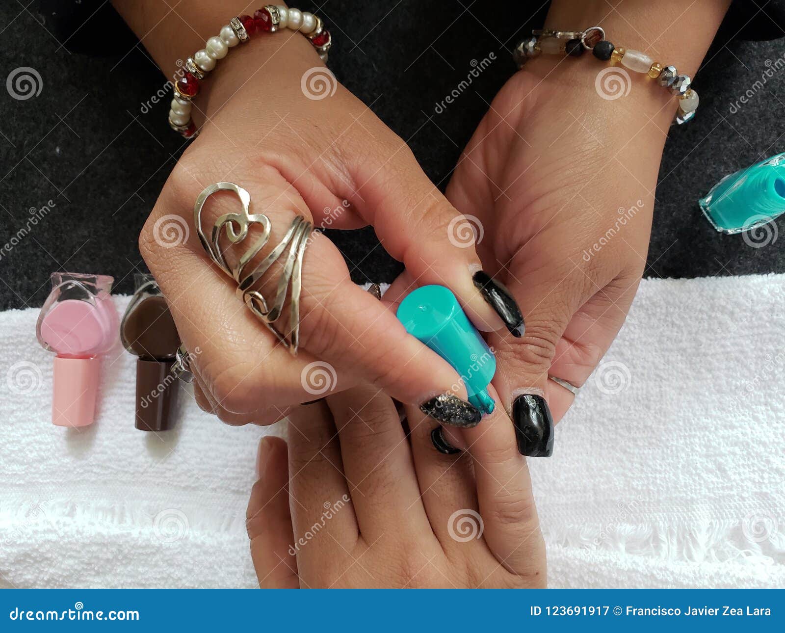 woman painting the fingernails of another woman with aquamarine nail polish