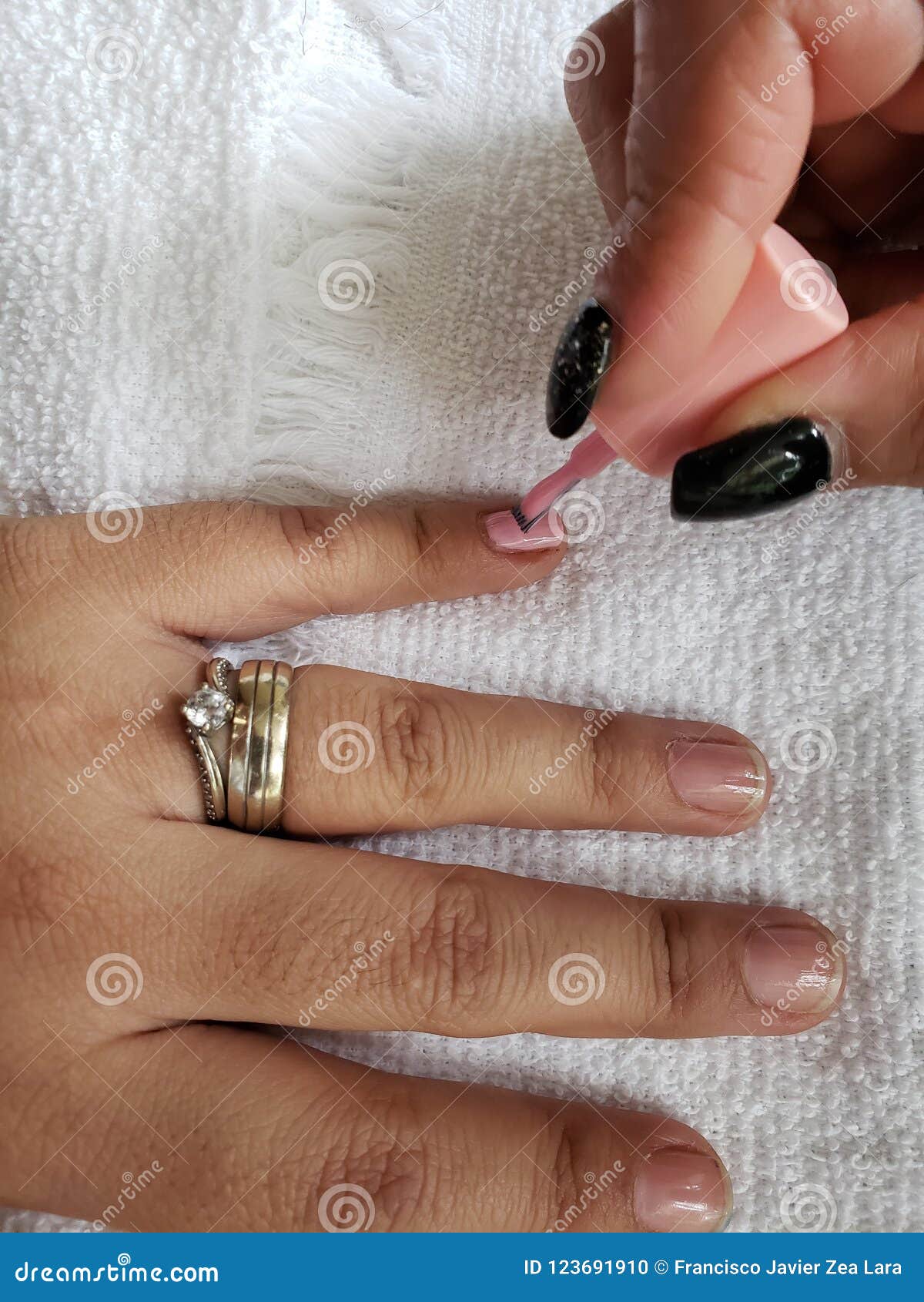 woman painting the fingernails of another woman with pink nail polish