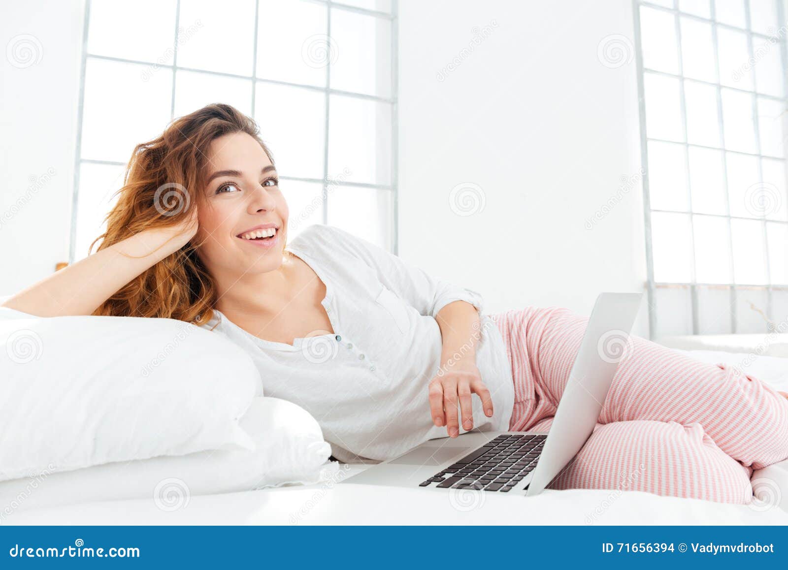 Woman in Pajamas Lying on the Bed with Laptop Computer Stock Photo ...