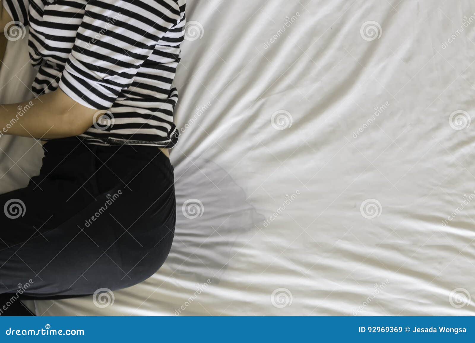 Lower Part of Female Body Wearing White Sleepwear Lying on Bed