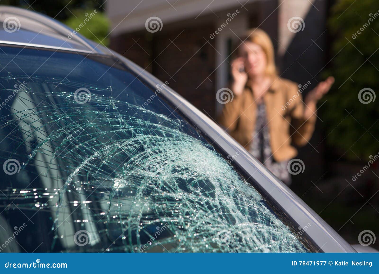 woman phoning for help after car windshield has broken