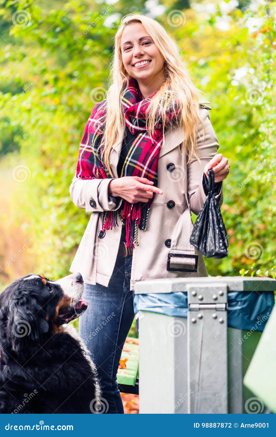 woman is picking up dog poo putting it in dustbin