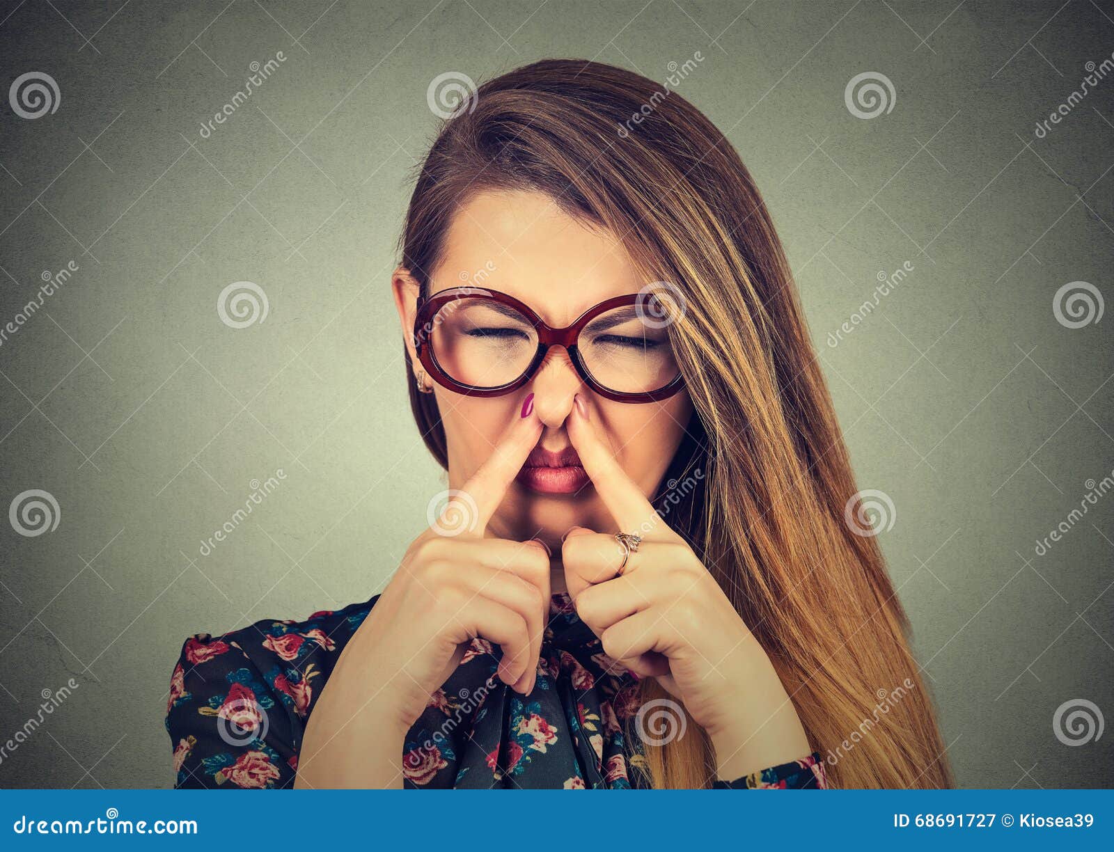 woman pinches nose with fingers looks with disgust bad smell