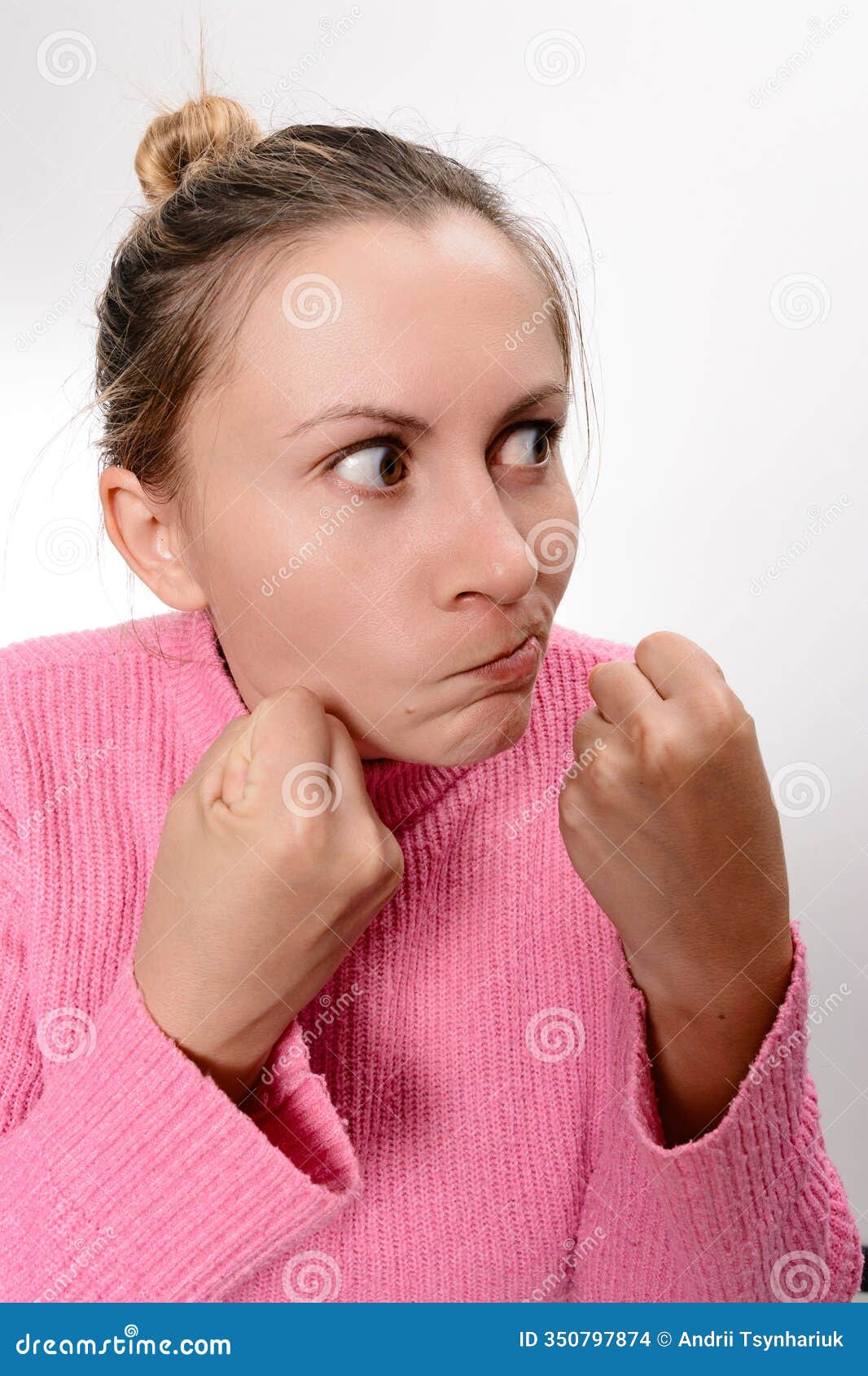 woman in pink sweater with clenched fists, looking determined.