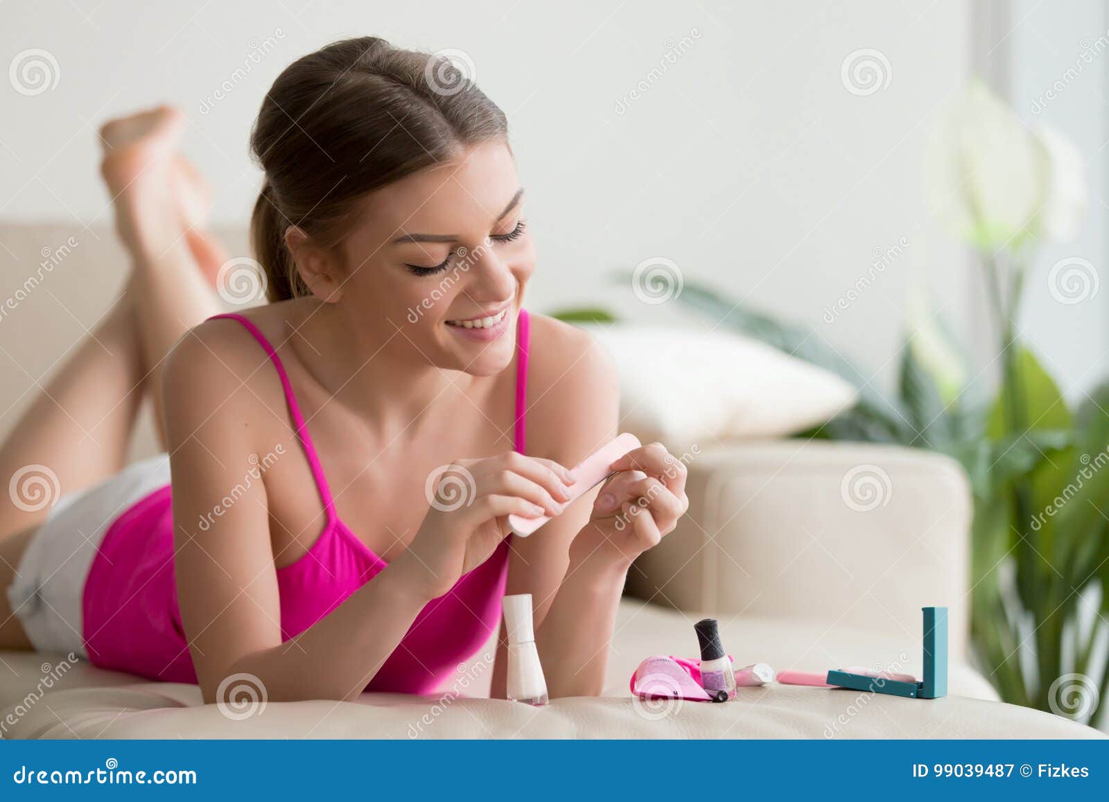 woman polishing nails with nail buffer at home
