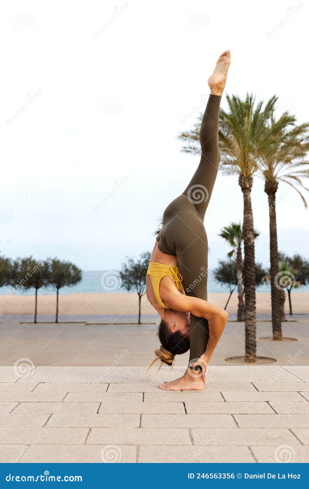 Young sporty woman standing vertical Split Pose practicing yoga at home.  Urdhva Prasarita Eka Padasana. Wellbeing and healthy lifestyle concept. -  Album alb9821362