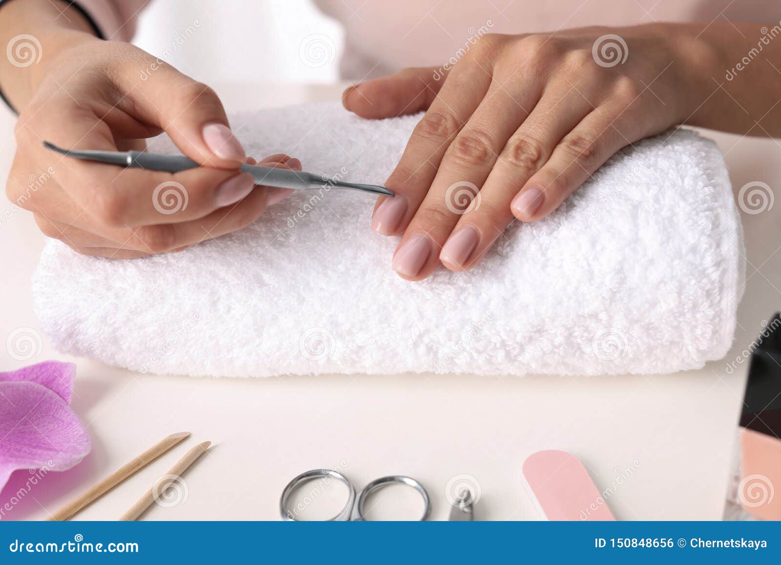 woman preparing fingernail cuticles at table. at-home manicure