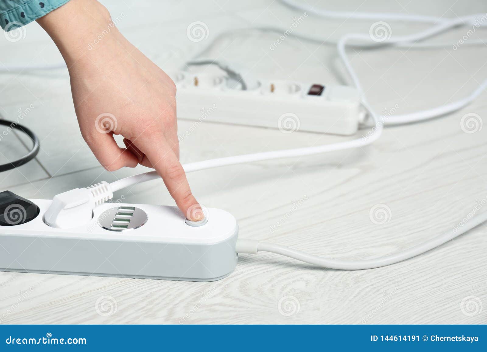 Woman Pressing Power Button Of Extension Cord On Floor Closeup