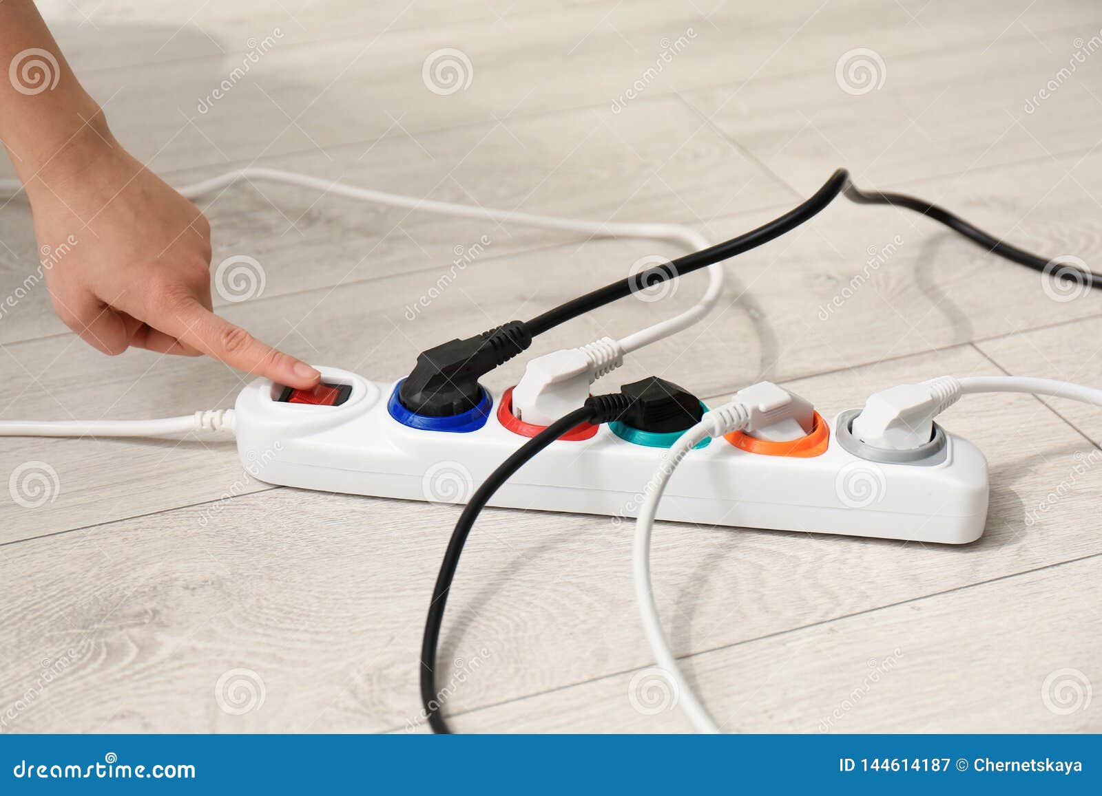 Woman Pressing Power Button Of Extension Cord On Floor Closeup