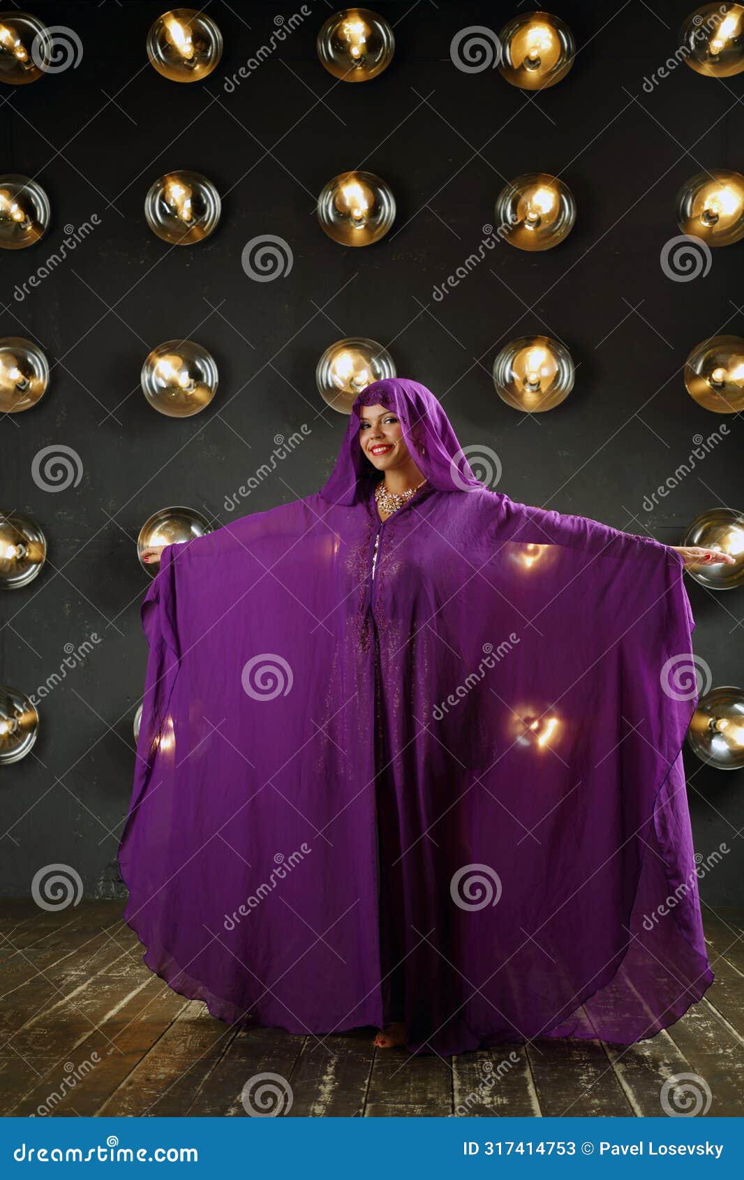 woman in purple mantle poses near wall with lamps