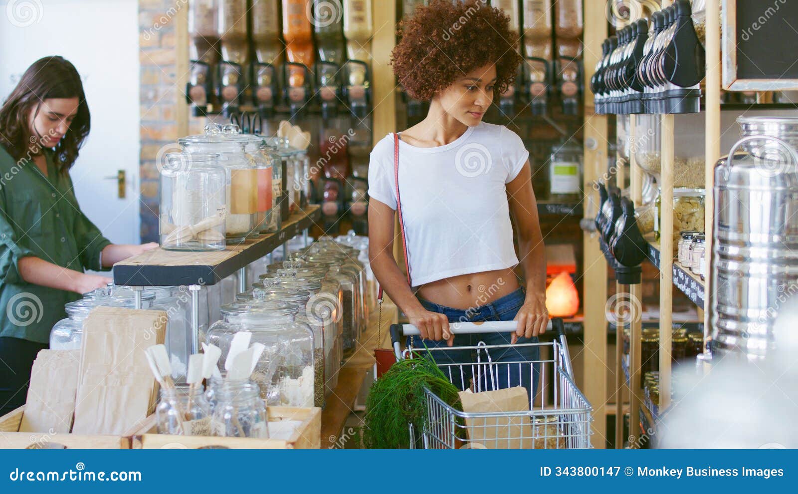 woman pushing shopping trolley looking at products in sustainable plastic free grocery store