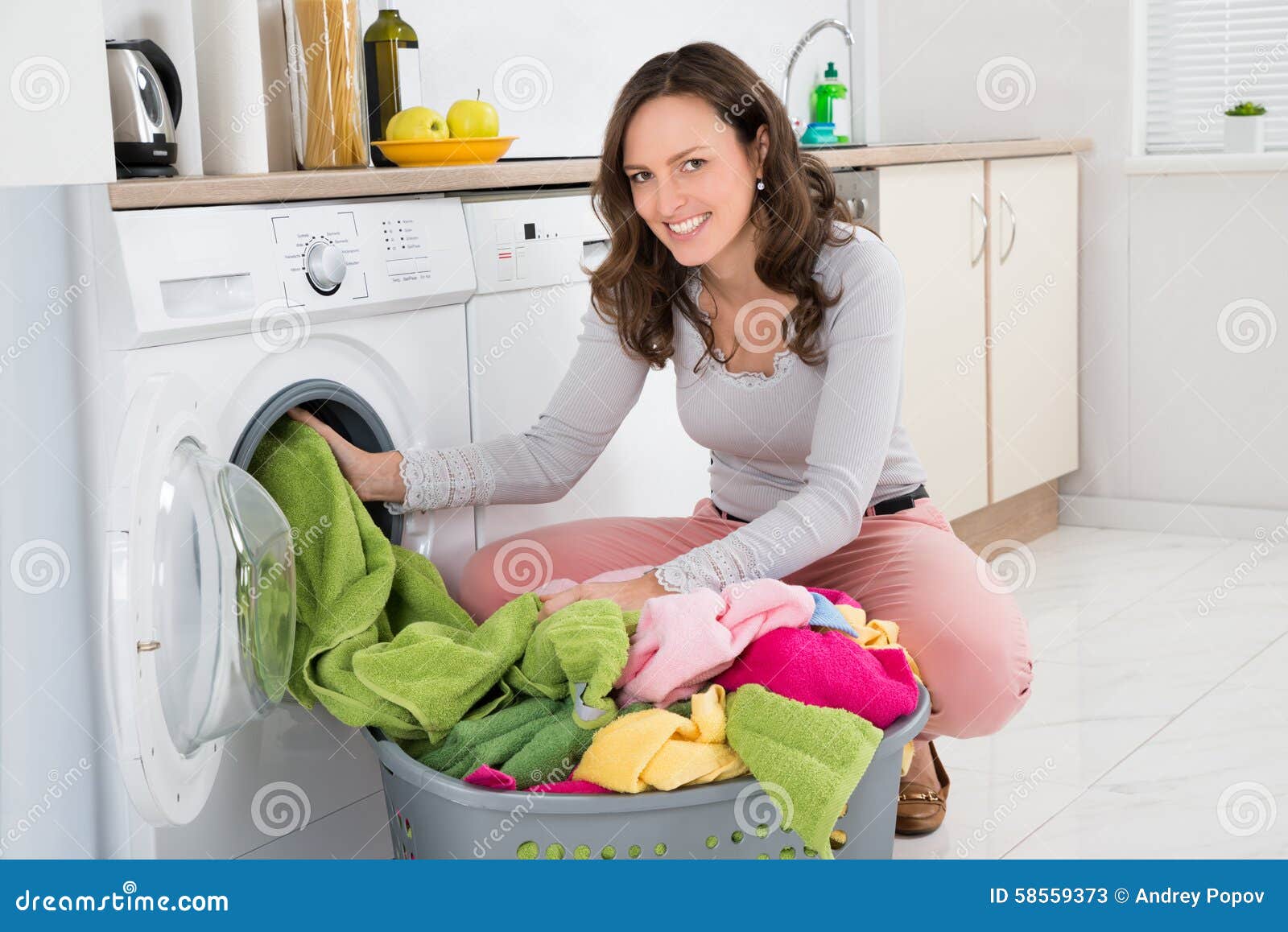 woman putting clothes into washing machine