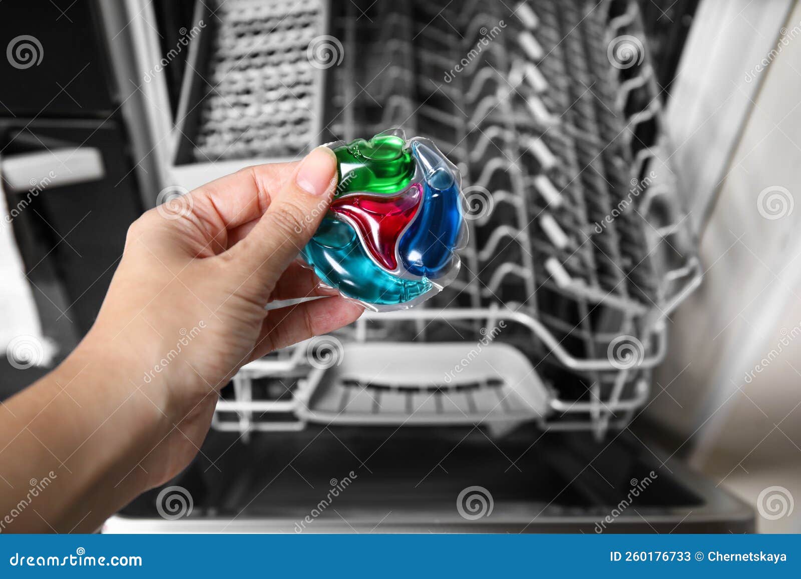 Woman Putting Detergent Pod into Open Clean Modern Empty Automatic Dishwasher Machine in Kitchen