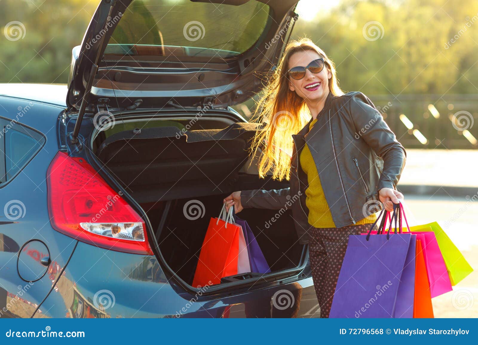 Smiling Caucasian woman putting her shopping bags into the car trunk